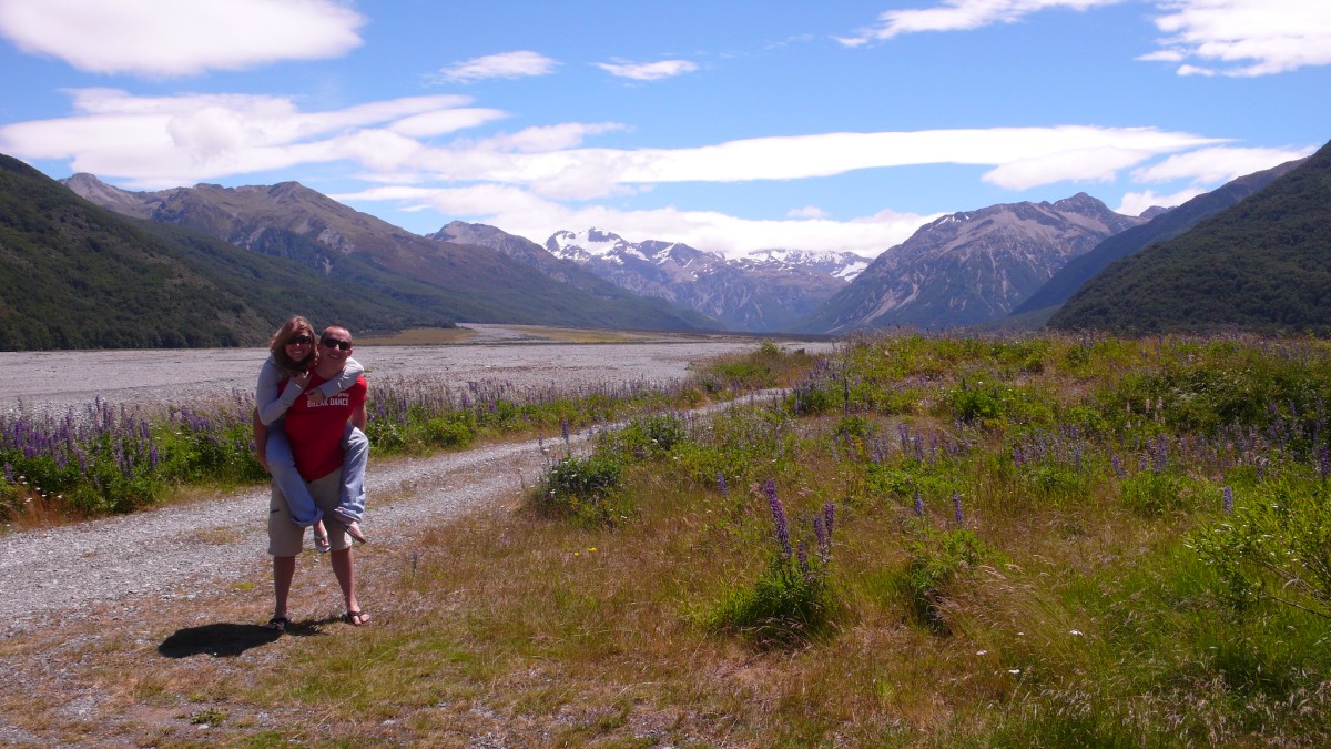 A majestic landscape of huge mountains far away with flat grassland and flowers in the foreground