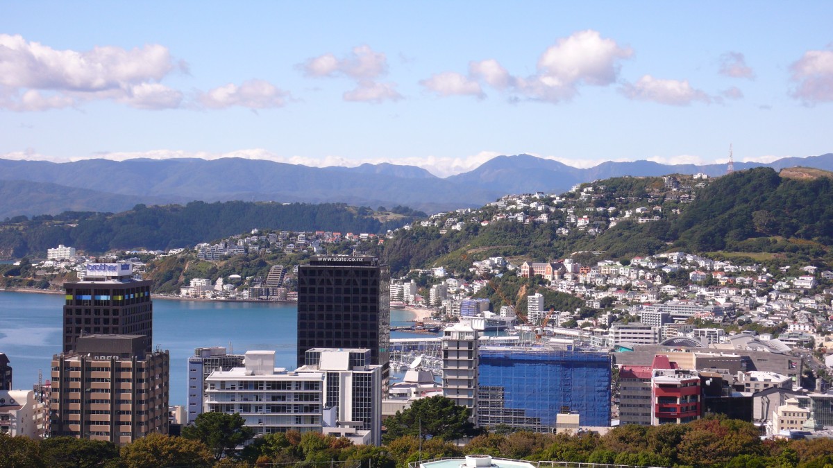 A bay surrounded by small buildings with mountains and forests in the background